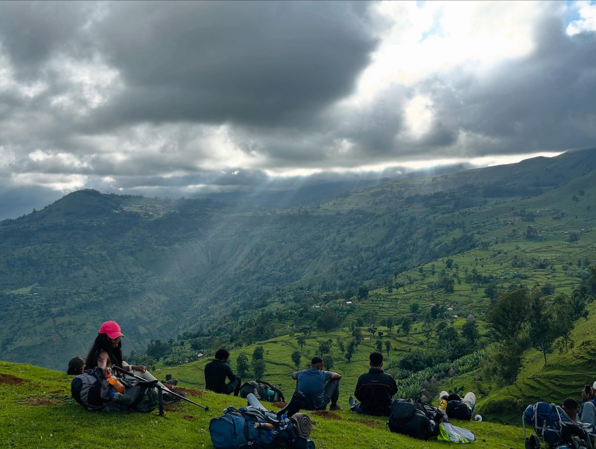 Hikers resting above a sunlit highland valley in Ethiopia